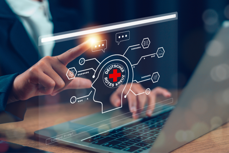 Das Imagebild zeigt einen Desktop als holografische Fläche. In die Oberfläche ist ein DRK-Logo eingearbeitet. Eine Hand tippt auf ein Symbol auf der Oberfläche.